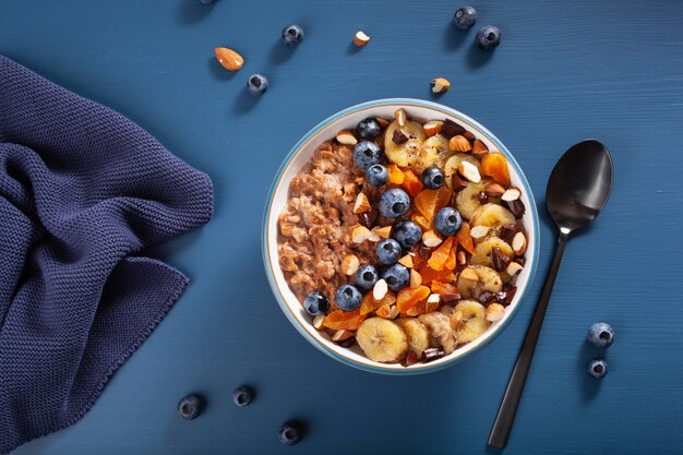 Gachas de avena y chocolate con arándanos, nueces, plátano, albaricoque seco para un desayuno saludable. Vista superior