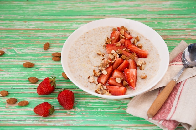 Gachas de avena con fresas y almendras en una placa blanca sobre un fondo rústico, copyspace