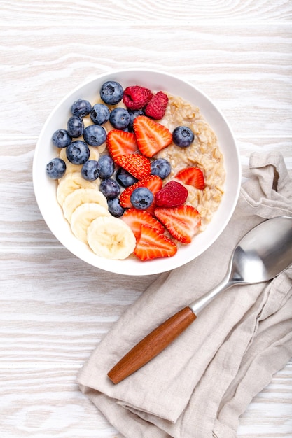 Gachas de avena con frutas y bayas en madera blanca