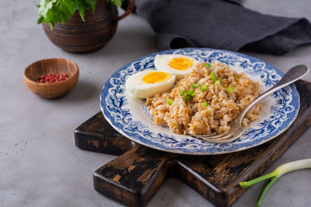 Gachas de avena gruesa con huevos y cebolla. Concepto de desayuno o almuerzo saludable abundante. Enfoque selectivo.