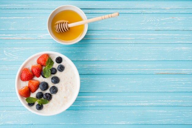 Gachas de avena con leche, bayas frescas y miel en un espacio rústico