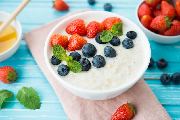 Gachas de avena con leche, bayas frescas y miel en un espacio rústico