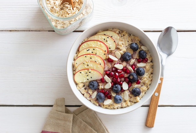 Gachas de avena con manzana, granada, arándanos y almendras. Alimentación saludable. Comida vegetariana. Desayuno.