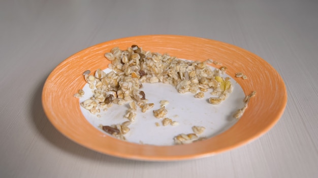 Foto gachas de avena con pasas en un plato con ribete naranja.