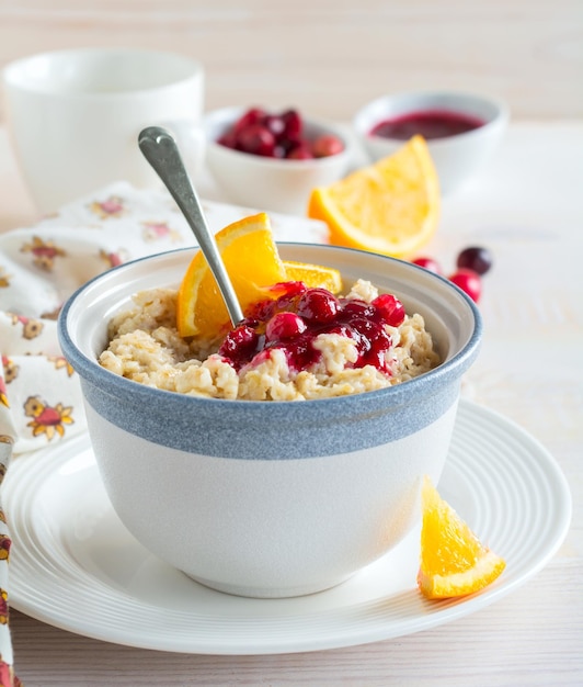 Gachas de avena con salsa de arándanos y naranja en un bol de cerámica para un desayuno saludable sobre un fondo claro. Enfoque selectivo.