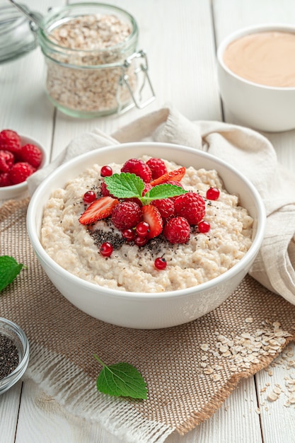 Gachas de avena saludable con frambuesas, fresas, grosellas rojas y semillas de chía sobre un fondo claro ...