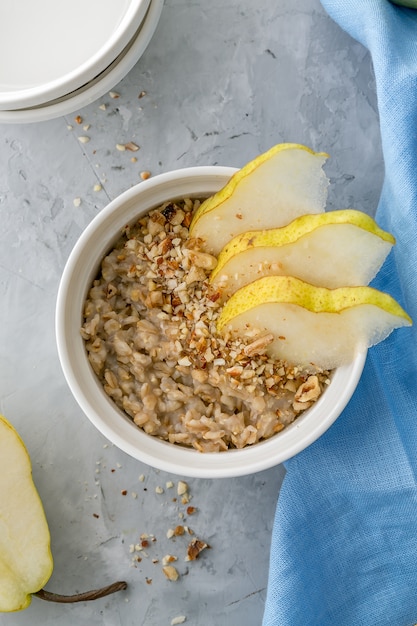 Gachas de avena saludables en un tazón con pera rebanada para el desayuno