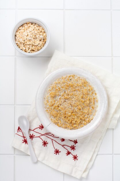 Gachas de avena simple con fresas en un plato blanco sobre una servilleta de lino. Concepto de comida sana de desayuno. Vista superior