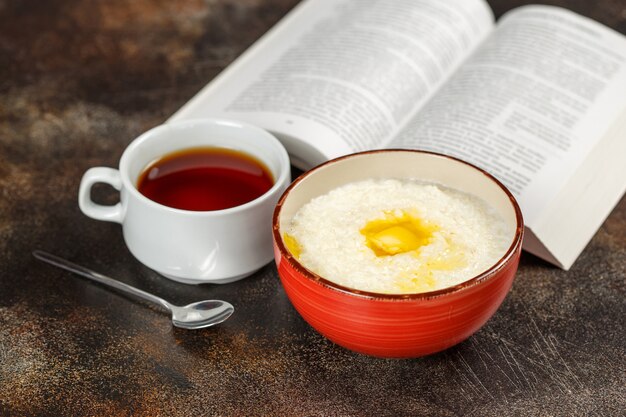 Gachas de avena en un tazón, té y libro