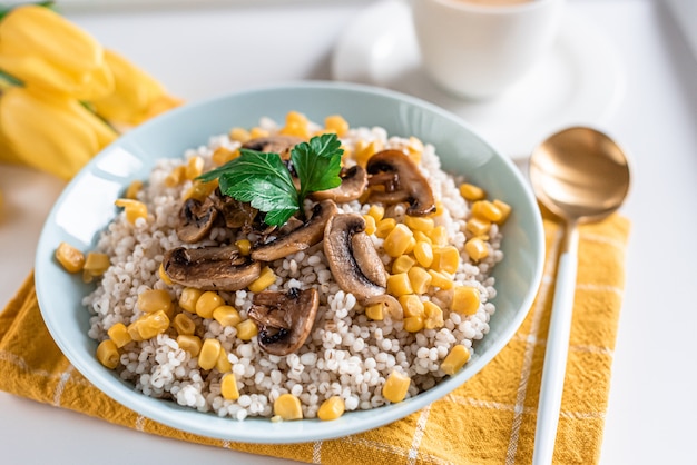 Gachas de cebada perlada con champiñones y maíz, concepto de comida saludable, desayuno, taza con café negro