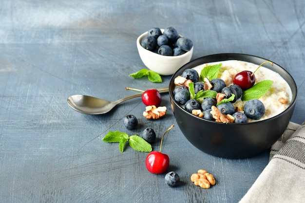 Gachas de cereal de avena con bayas frescas en un tazón negro.