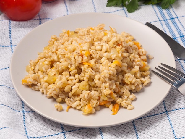 Gachas de perlas con cebollas y zanahorias en un plato en un café