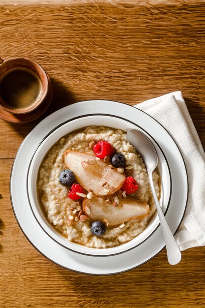 Gachas de quinoa con pera caramelizada y bayas en una mesa de madera desayuno matutino con café