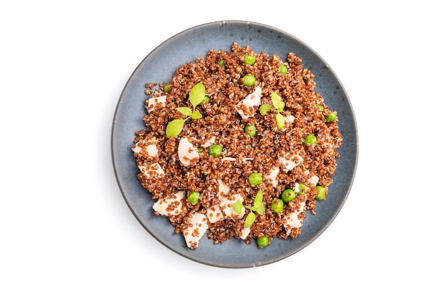 Gachas de quinua con guisantes verdes y pollo en plato de cerámica aislado en superficie blanca