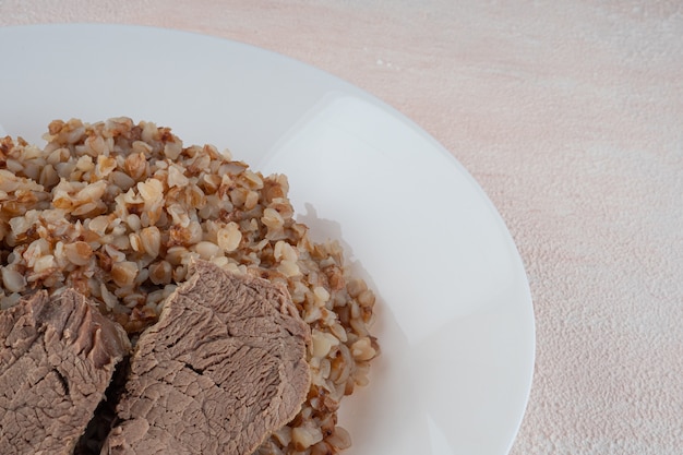 Gachas de trigo sarraceno con tres trozos de carne hervida en un plato blanco