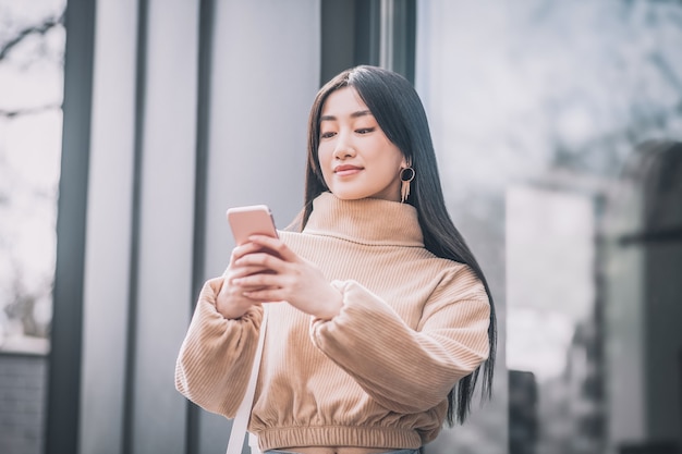 Gadget. Muito jovem mulher asiática segurando um smartphone nas mãos