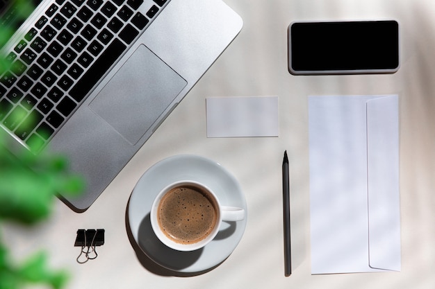 Gadgets, café, herramientas de trabajo en una mesa blanca en el interior.