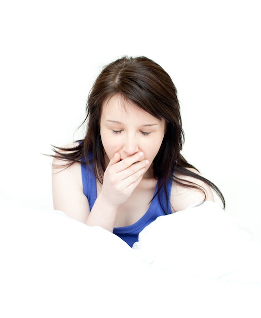 Gähnendes Sitzen der bezaubernden Frau auf ihrem Bett