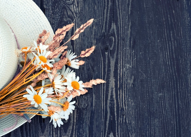 Gänseblümchen auf dem Hintergrund eines Sommerstrohhutes