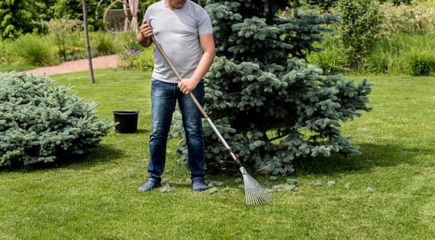 Gärtner, der Blätter im Garten harkt.