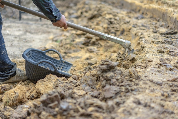 Gärtner gräbt den Boden mit seiner Ausrüstung für die Gartenarbeit und bereitet Land für die Plantage vor.