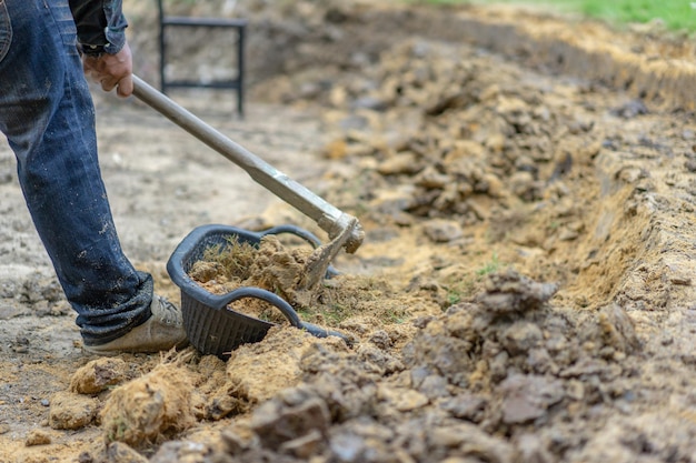 Foto gärtner gräbt den boden mit seiner ausrüstung für die gartenarbeit und bereitet land für die plantage vor.