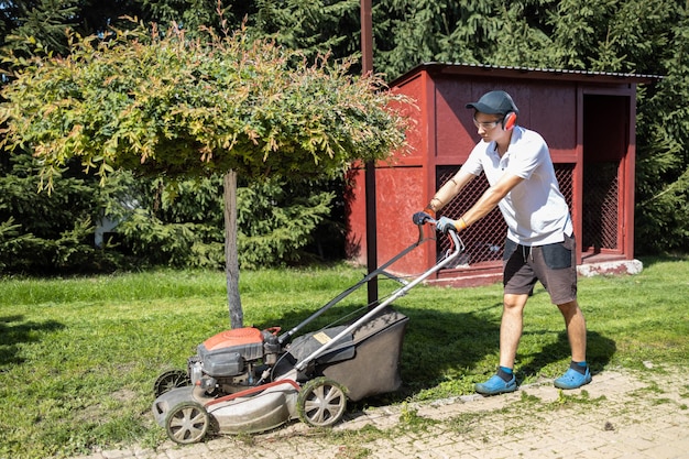 Gärtner mäht das Gras mit Benzin-Rasenmäher