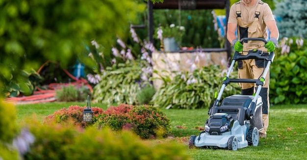 Gärtner schneidet Gras mit Elektromäher