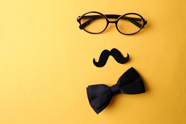 Gafas bigote y pajarita formando cara de hombre sobre fondo amarillo