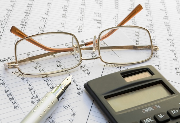 Gafas, calculadora y bolígrafo de cerca