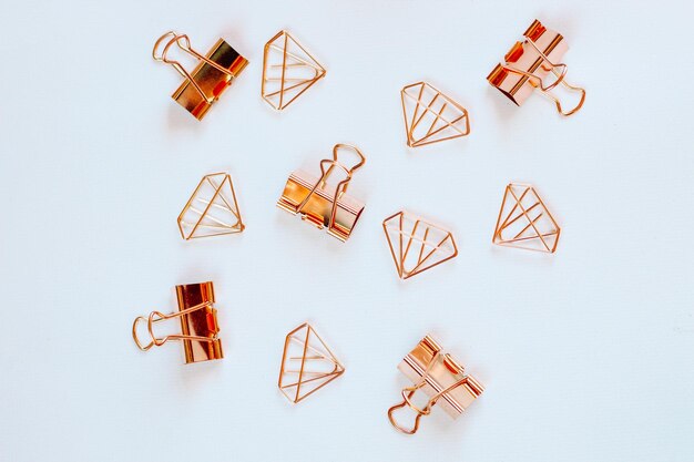 Gafas clips de papel en forma de diamantes de oro rosa sobre un fondo blanco.