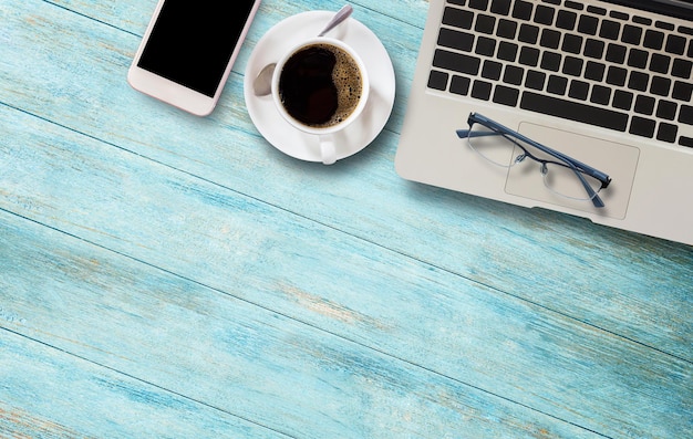 Gafas de computadora portátil y taza de café en la mesa de madera