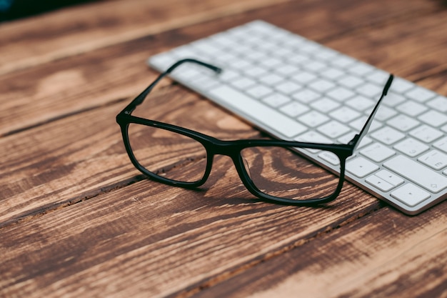 Gafas para la corrección de la vista y la visión y la protección de la computadora en la mesa de madera en el teclado