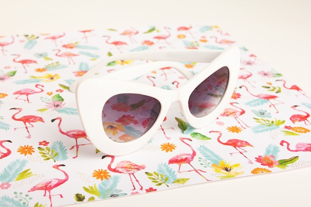 Gafas de sol blancas de moda sobre um fondo de flores