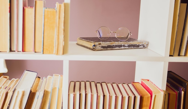 Las gafas están en un libro viejo y en mal estado en una estantería de la biblioteca Concepto de lectura de libros