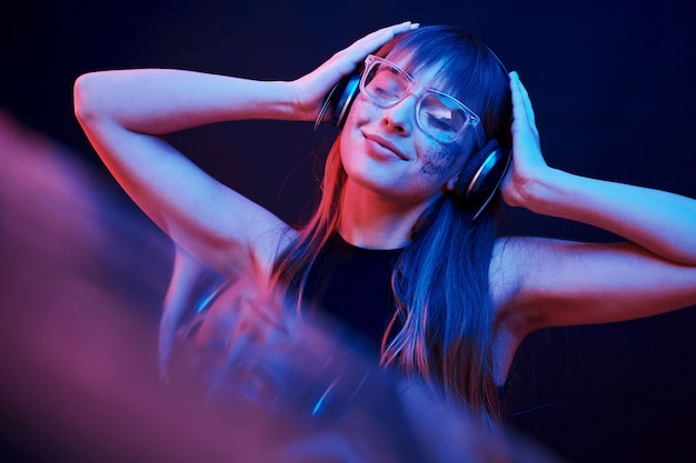 Gafas con estilo. Foto de estudio en estudio oscuro con luz de neón. Retrato, de, niña joven