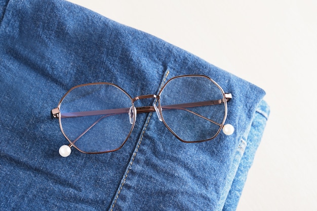 Gafas con estilo en una pila de jeans en la vista superior del espacio de copia de fondo de madera