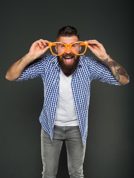 Las gafas hacen más que mejorar su visión. Hombre barbudo con gafas elegantes sobre fondo gris. Hipster brutal mirando a través de accesorios de gafas de moda.