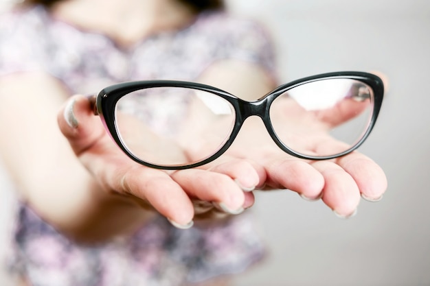 gafas en mano femenina, gafas en mano de mujer, manos extendidas con gafas, recostarse en las palmas