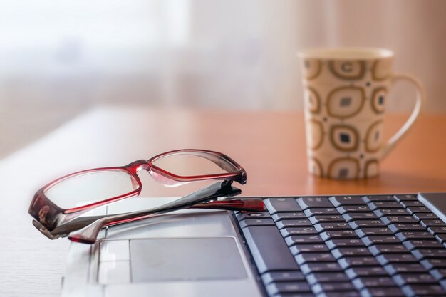 En las gafas de mentira del portátil, más allá de la mesa hay una taza