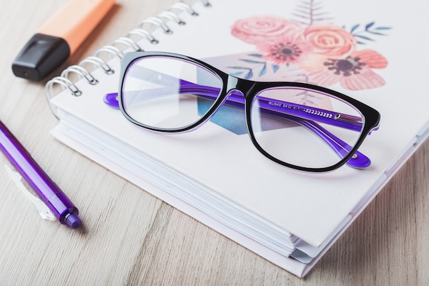 Foto gafas mujer con agenda y lápices