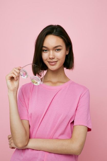 Gafas de mujer joven en forma de diamantes en una camiseta rosa fondo rosa
