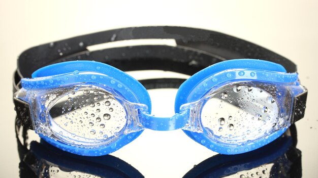 Foto gafas de natación azules con gotas sobre fondo gris