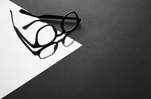 Foto gafas negras de moda en superficie reflectante