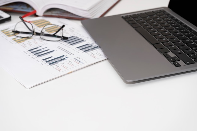 Gafas de portátil y diagramas en la mesa blanca Concepto de investigación analítica y finanzas empresariales