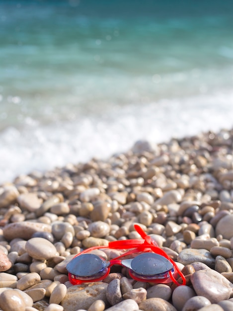 Gafas rojas para nadar en el agua se encuentran en la playa