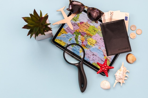 Gafas de sol avión pasaporte dinero tableta con mapa conchas estrellas de mar fondo para viajes publicidad banner concepto de viaje