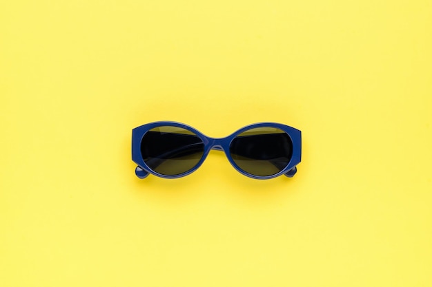 Gafas de sol azul oscuro sobre un fondo amarillo Concepto mínimo de verano Lay Flat