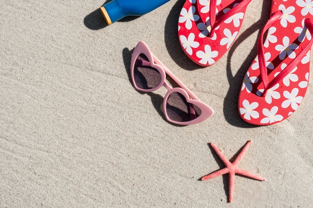 Gafas de sol y chanclas en la playa tropical de arena blanca, vacaciones de verano y concepto de viaje