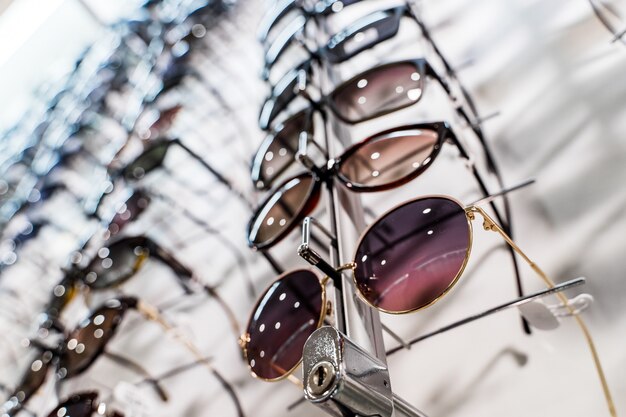 Gafas de sol en los estantes de exhibición de la tienda. De pie con gafas en la tienda de óptica.